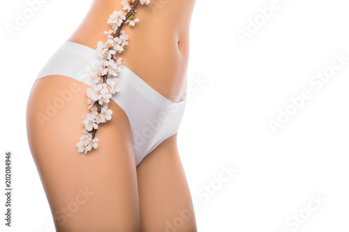 perfect female body with flower, isolated on a white background, part of the body - stomach and thighs, in white underwear, close-up. female health and gynecology