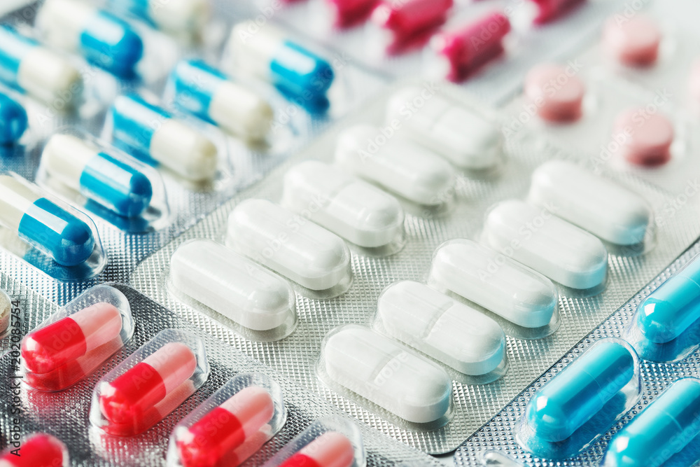 Heap of medical pills in white, blue and other colors. Pills in plastic package. Concept of healthcare and medicine. Heap of medical pills in white, blue and other colors. Pills in plastic package. Concept of healthcare and medicine.