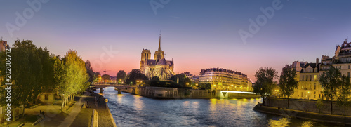 Panoramic view of Notre Dame (famous Paris landmark) along the Seine river at twilight, sunset, amazing pano with vibrant color sky