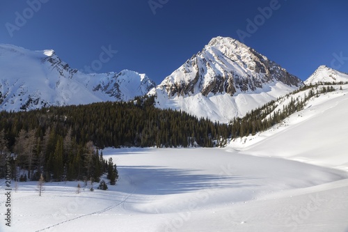 Scenic Winter Landscape View of Frozen Chester Lake and Snowy Mountain Peaks in Kananaskis Country near Banff National Park, Canadian Rockies Alberta Canada