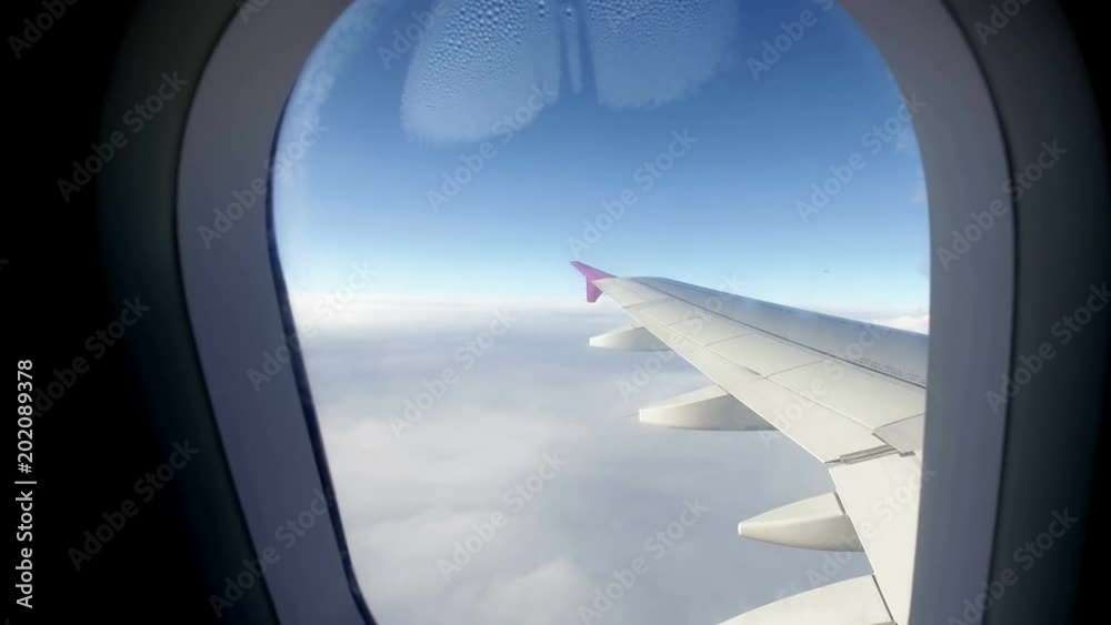Passenger POV looking through the Window of plane flying over clouds Passenger POV looking through the Window of plane flying over clouds