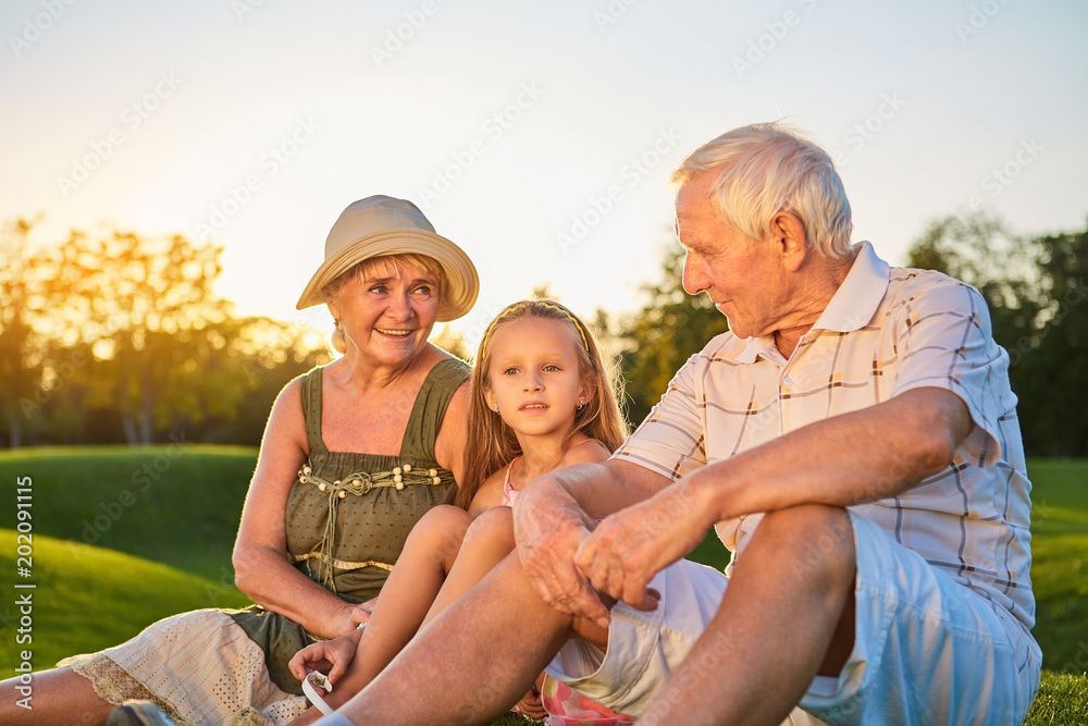 Senior man and woman, granddaughter. People sitting outdoors. How to pass on wisdom.