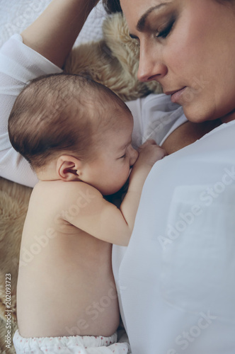 Top view of young mother hugging her newborn baby girl lying on the bed photo