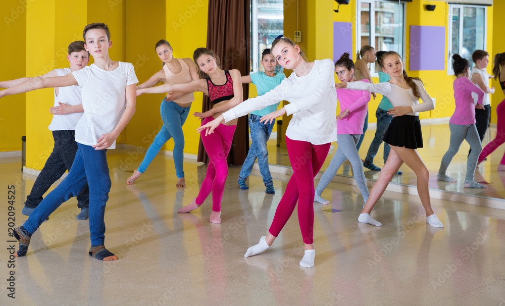 Teenagers dancers practicing dance routine with female choreographer in modern studio