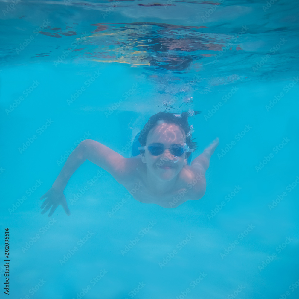 Pre-teen Boy Swimming Underwater in Pool with Smile