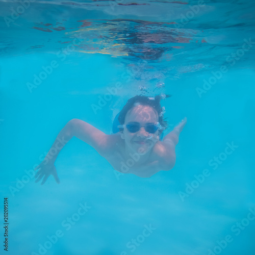 Pre-teen Boy Swimming Underwater in Pool with Smile