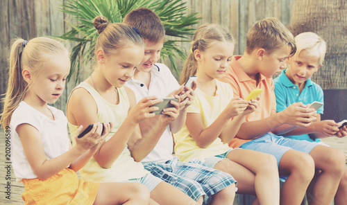 Busy children holding smartphones  and sitting