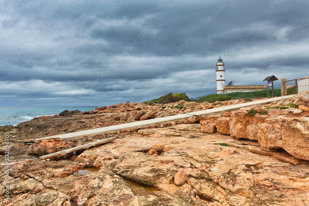 Island scenery with rocks and sea in gloomy weather, lighthouse