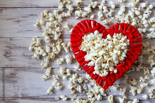 Tasty popcorn on red wooden heart. Top view. photo