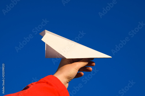 White paper airplane in hand against the sky. A symbol of freedom on the Internet. photo