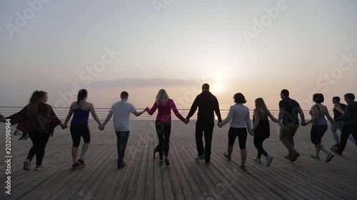 Group of young casual people walking together hand in hand.  The concept of peace, friendship, happiness, success and achievement photo