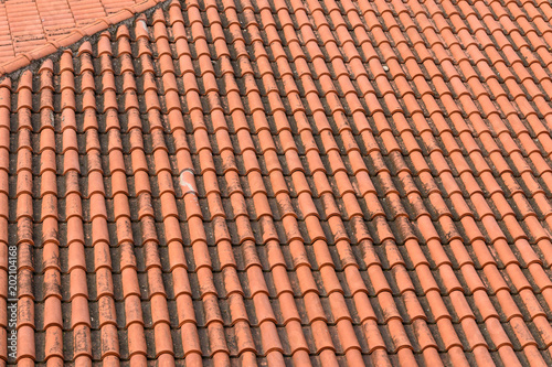 Top view of old and weathered clay tile roof, pattern of orange tiles © Emil