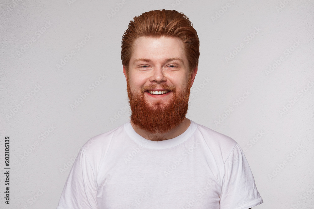 Indoor portrait of attractive handsome ginger man with beard, has positive expression, isolated over white studio background. Emotions concept Indoor portrait of attractive handsome ginger man with beard, has positive expression, isolated over white studio background. Emotions concept