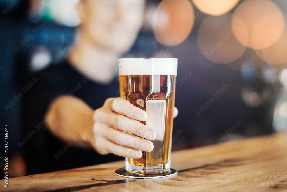 Bartender man stretches out a glass of beer.