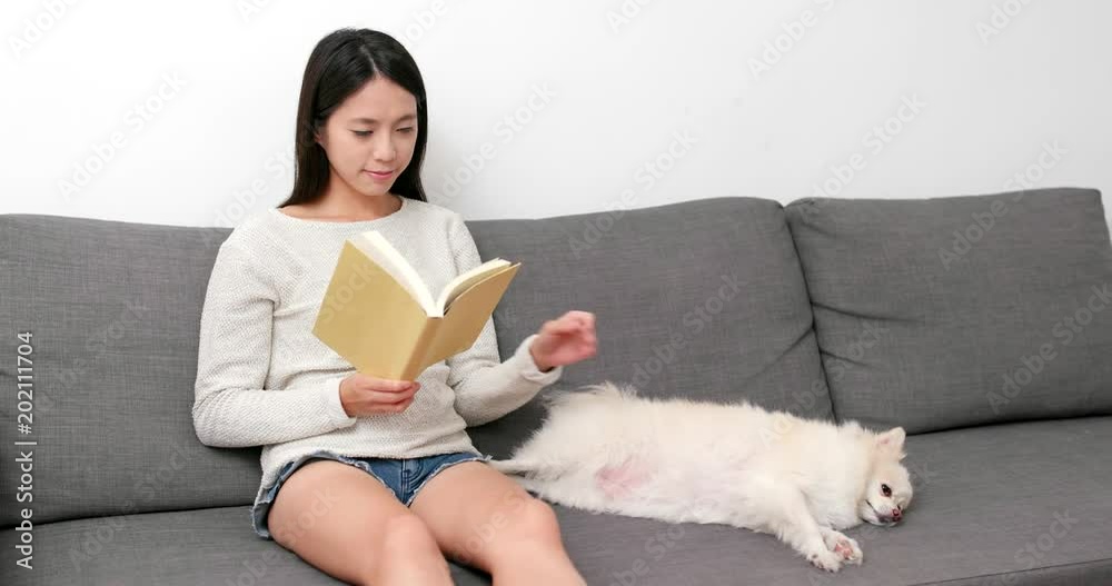 Woman reading book with her dog at home Woman reading book with her dog at home
