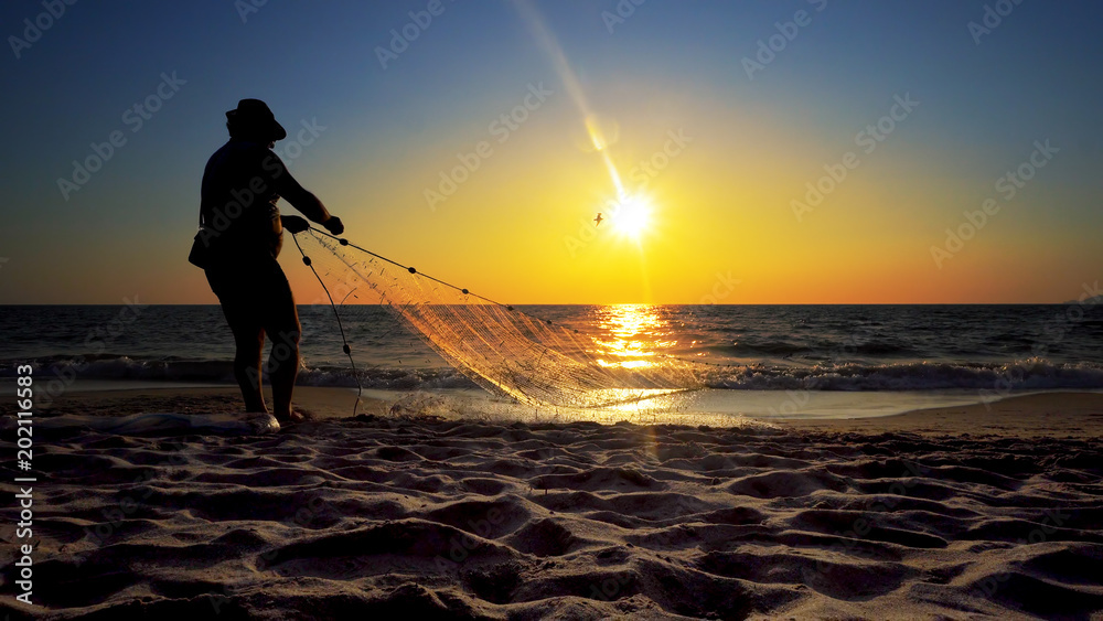 Fisherman on ocean coast with net  in action when fishing, cinematic shot