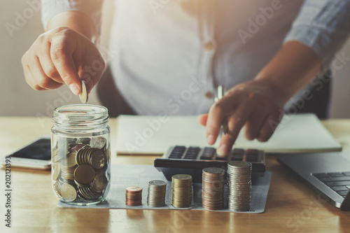 businesswoman hand puting coins in glass for saving money. concept finance and accounting