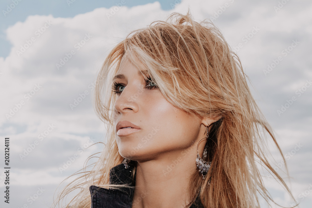 Portrait of blonde on cloudy sky background