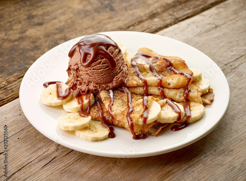 Crepes with banana and chocolat icecream on wooden desk