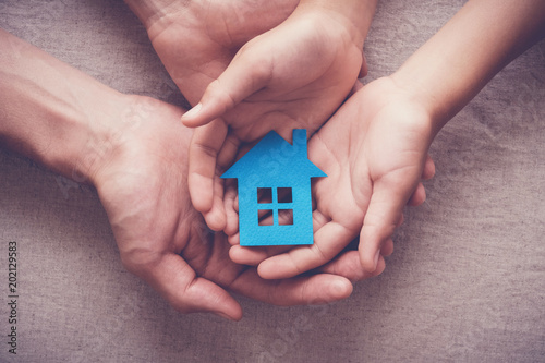 Adult and child hands holding paper house, family home, homeless shelter, foster home care, family day care, social distancing, stay at home concept