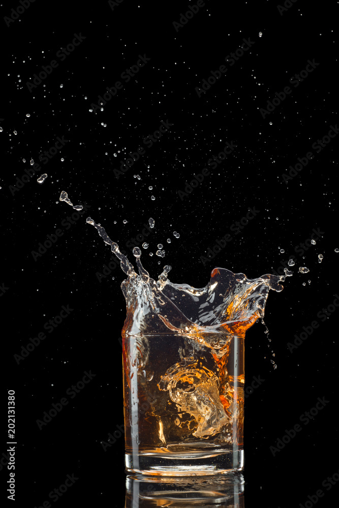 Glass of whiskey with splash isolated on black background Glass of whiskey with splash isolated on black background
