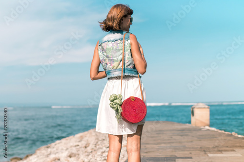 Woman with fashionable stylish red rattan bag and silk scarf outside. Tropical island of Bali, Indonesia. Rattan handbag and silk scarf. photo