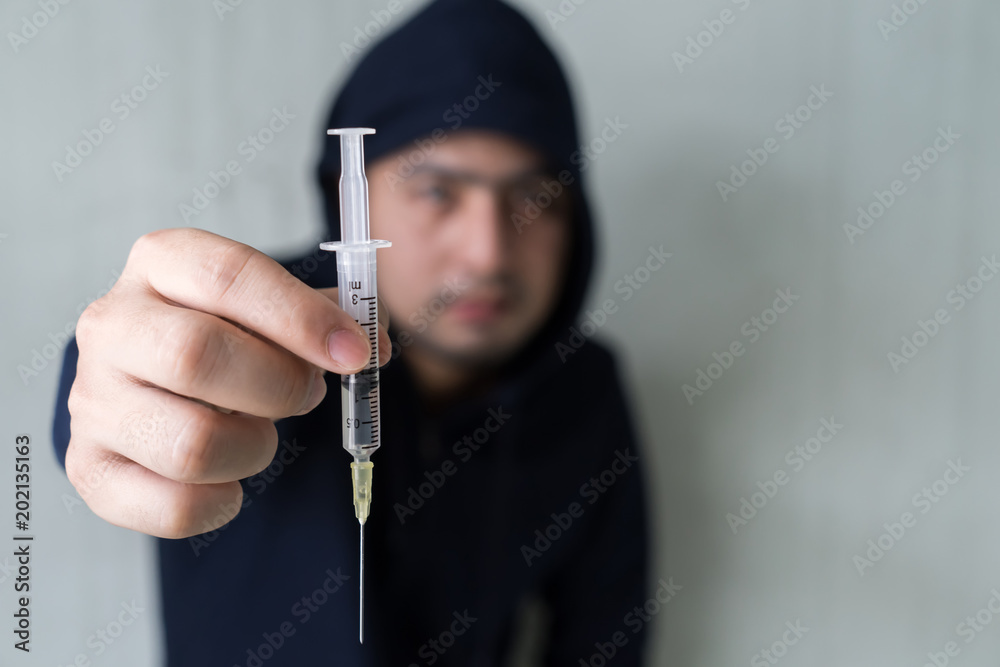 Addict man with syringe using drugs. Drug addict boy holding syringe with drugs. Addict man with syringe using drugs. Drug addict boy holding syringe with drugs.