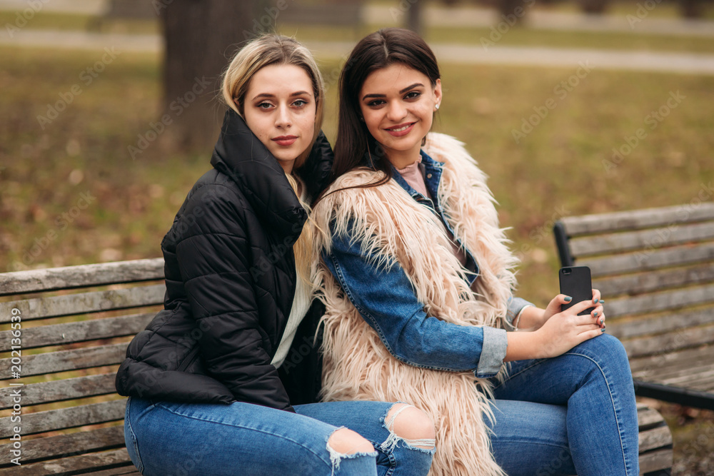 Two girls sitting on the bench outdoors Two girls sitting on the bench outdoors