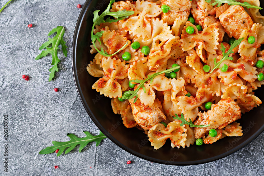Farfalle pasta with chicken fillet, tomato sauce and green peas. Italian Cuisine. Food menu. Top view. Dinner.