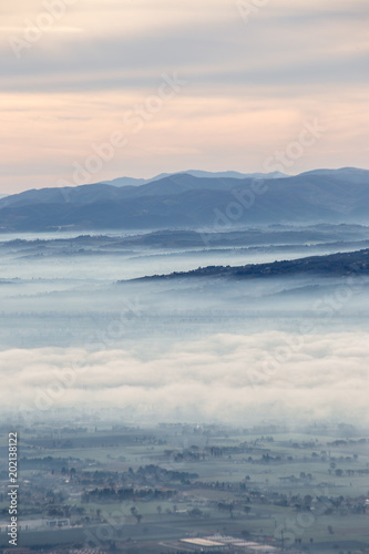 Beautiful aerial view of Umbria valley in a winter morning, with fog covering trees and houses