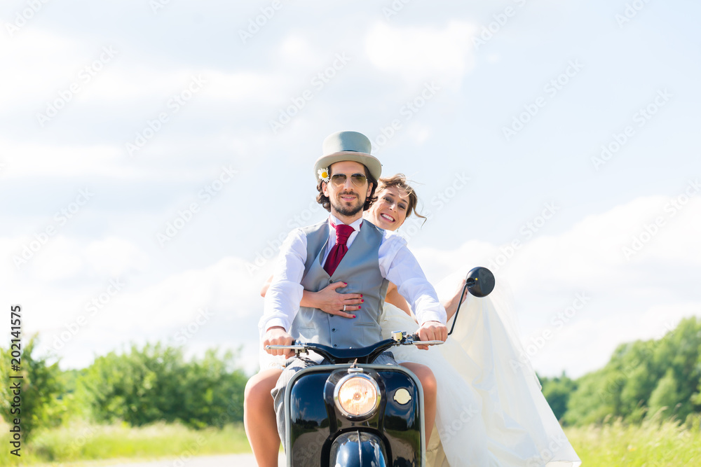 Wedding groom and bride driving motor scooter having fun 