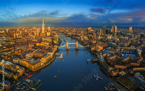 London, England - Panoramic aerial skyline view of London including iconic Tower Bridge with red double-decker bus, Tower of London, skyscrapers of Bank District at golden hour early in the morning