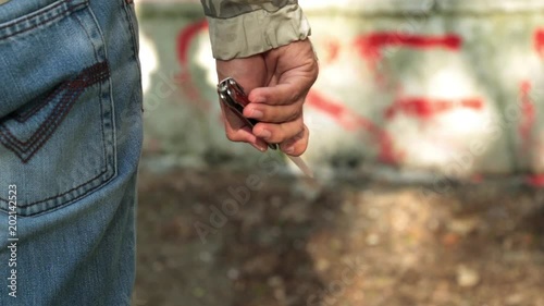 A man is a criminal with a knife in his hand, close-up. A bully in the street.