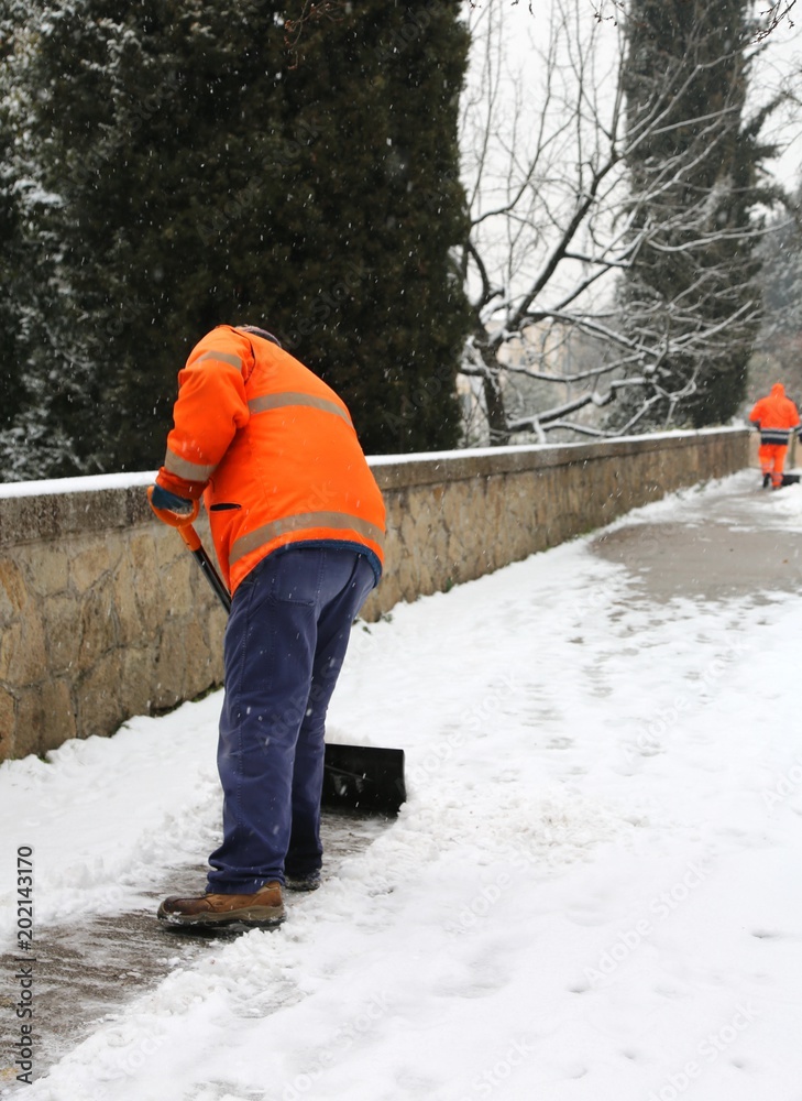 Fototapeta premium garbage man shovels the snow from the pavement after heavy snowfall