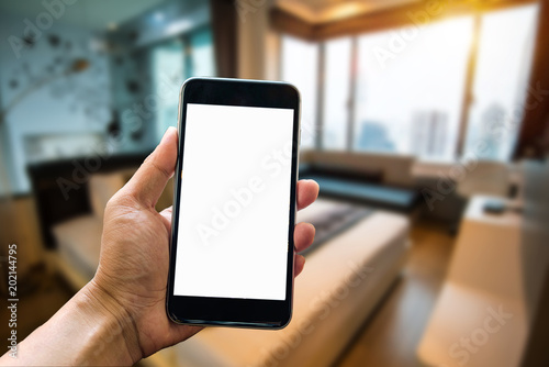 A man hand holding smart phone device in the bright office room interior. 