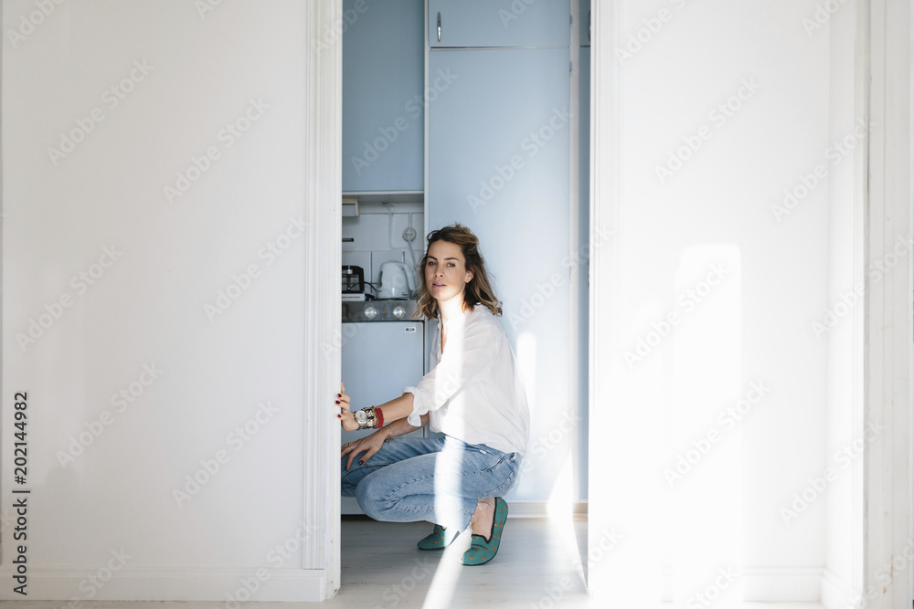 Young woman crouching in kitchen Young woman crouching in kitchen