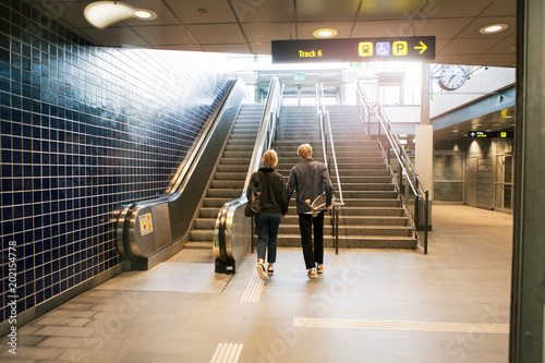 Full length rear view of young couple walking towards staircase at subway station photo