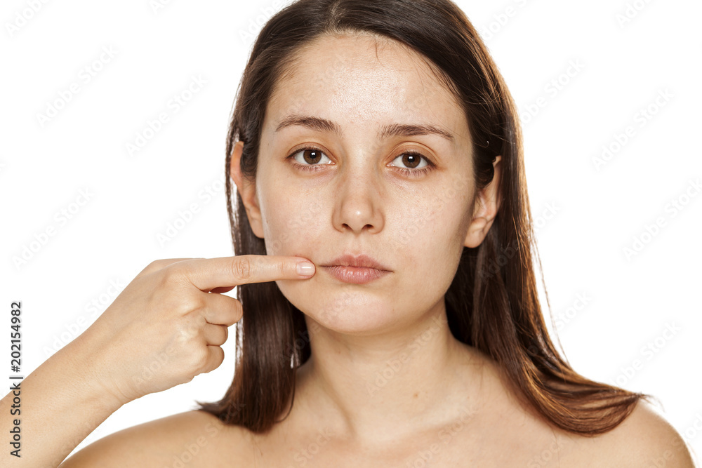 Young woman pointing on her lips on white background Young woman pointing on her lips on white background