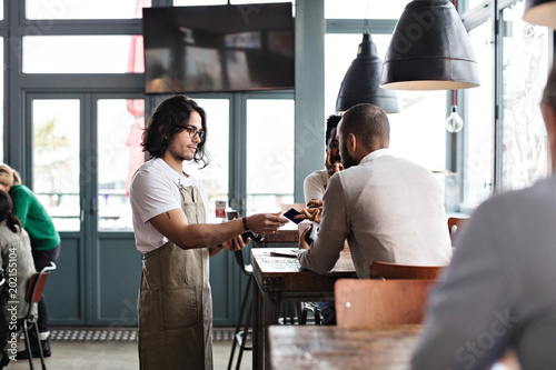 Waiter accepting payment from customer in cafe