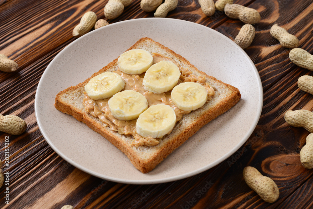 Peanut butter toast with banana slices  on wooden background
