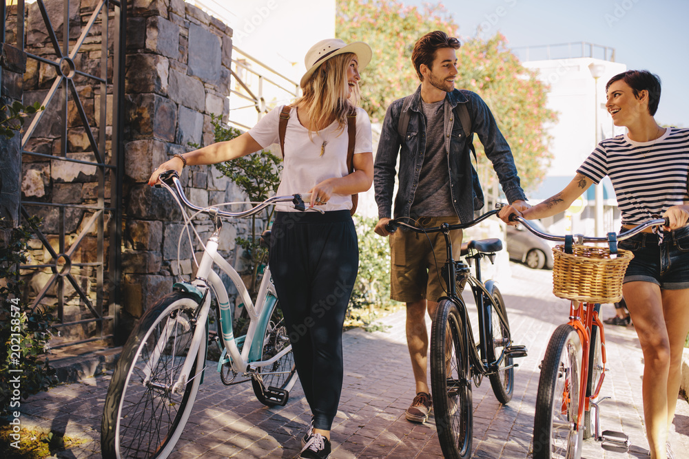 Obraz premium Friends with bikes walking outdoors in city
