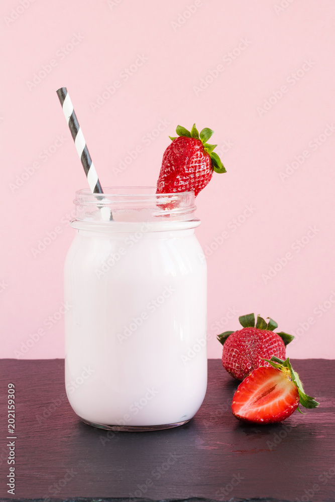Strawberry milkshake with berry in mason jar on pink. Close up. Summer drink. Strawberry milkshake with berry in mason jar on pink. Close up. Summer drink.