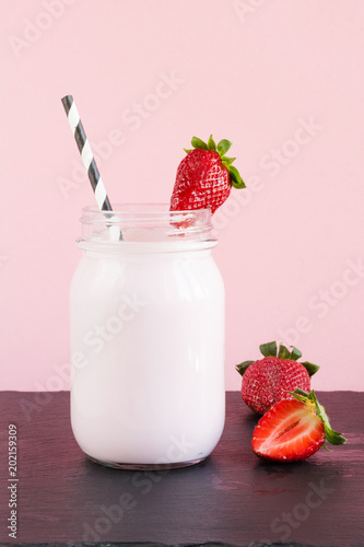 Strawberry milkshake with berry in mason jar on pink. Close up. Summer drink.