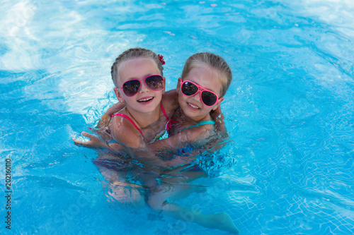 Two little funny girl in the pool on holiday