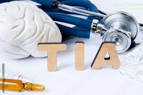 TIA Acronym or abbreviation to medical concept or diagnosis of transient ischemic attack or small brain stroke. Word TIA stands among models of the brain, stethoscope and medicines in ampules or vials