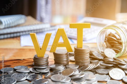 Vat Concept.Word vat with stacked coins there is a notebook calculator on the desk.VAT photo