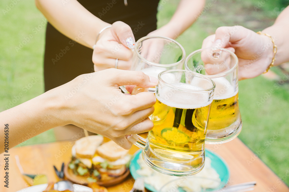 Close-up cropped image of friends clinking with beer in garden. Close-up cropped image of friends clinking with beer in garden.