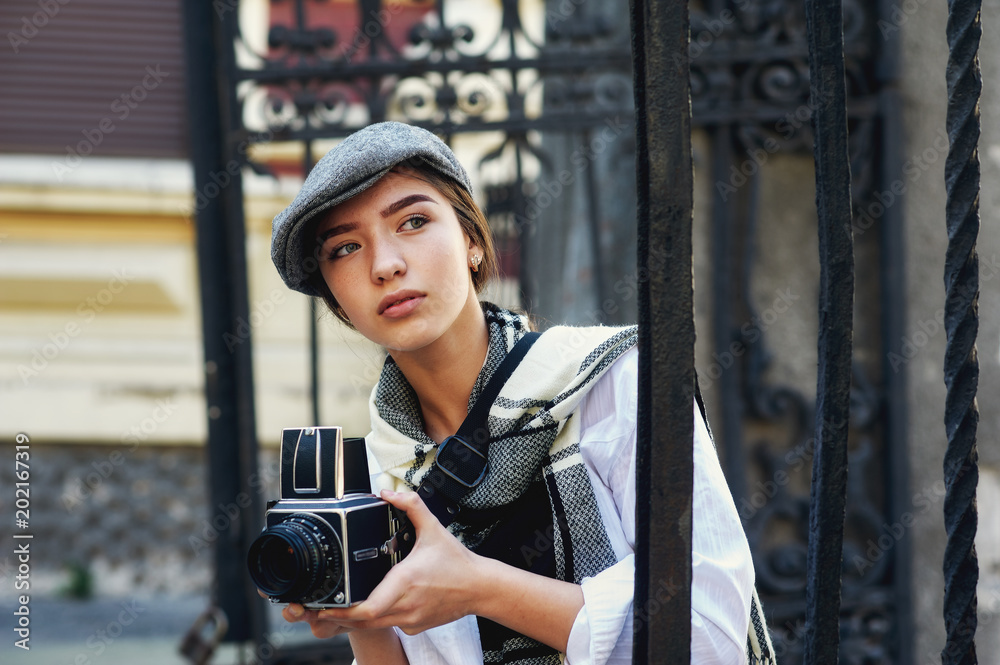 Girl photographer with an old camera in his hands .Stylish fashionable girl photographer in the city street