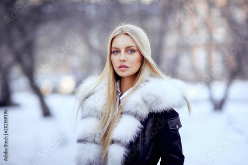 Young woman in fur coat standing outside photo