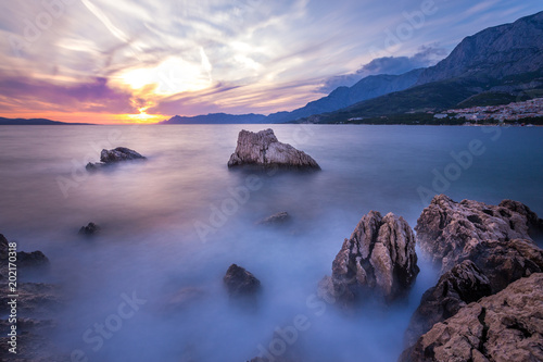 Langzeitbelichtung - Farbenfroher Sonnenuntergang mit Felsen, Gebirge und Wolken am Meer IV © Michael